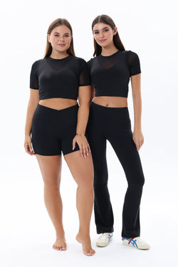 Image of Two women wearing black atheisure outfits stretch flare leggings anf mesh croptop 